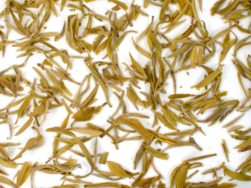 Zhi Xiang Ganlu (Gardenia Sweet Dew) scented green tea leaves floating in clear water.