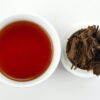 Cupped infusion of Naka Sun-Dried black tea and strained leaves.