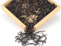 Dongfang Hong (The East Is Red) Dan Cong wulong tea dry leaves displayed on a bamboo tray.