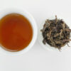 Cupped infusion of Fenghuang Dan Cong (Sky Feather) wulong tea and strained leaves.