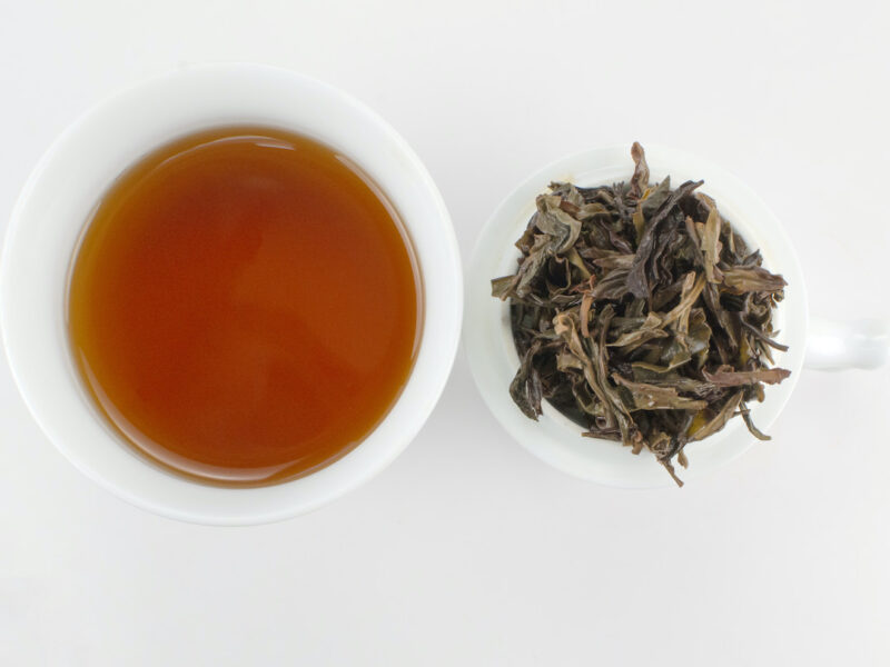 Cupped infusion of Fenghuang Dan Cong (Sky Feather) wulong tea and strained leaves.