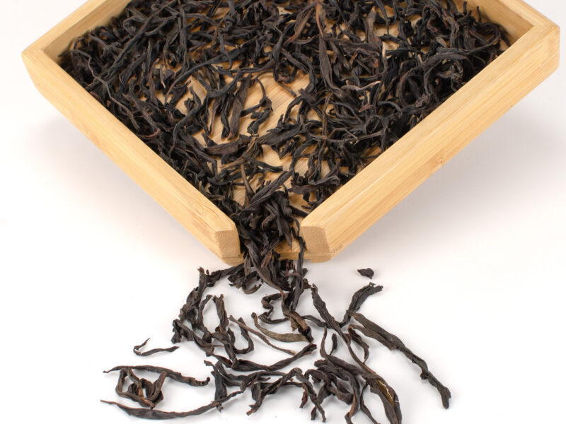 Fenghuang Dan Cong (Sky Feather) Dan Cong wulong dry tea leaves displayed on a bamboo tray.
