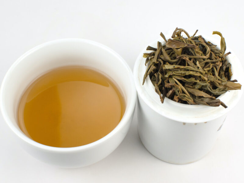 Cupped infusion of Youle Huangshancha (Youle Forest Tea) sheng puer tea and strained leaves.