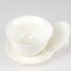 A white porcelain gaiwan with its lid opened and resting on its side.