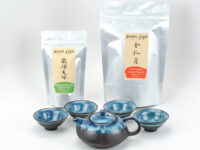 The two teas and tea set included in The Essentials Kit, with one teapot and four teacups.