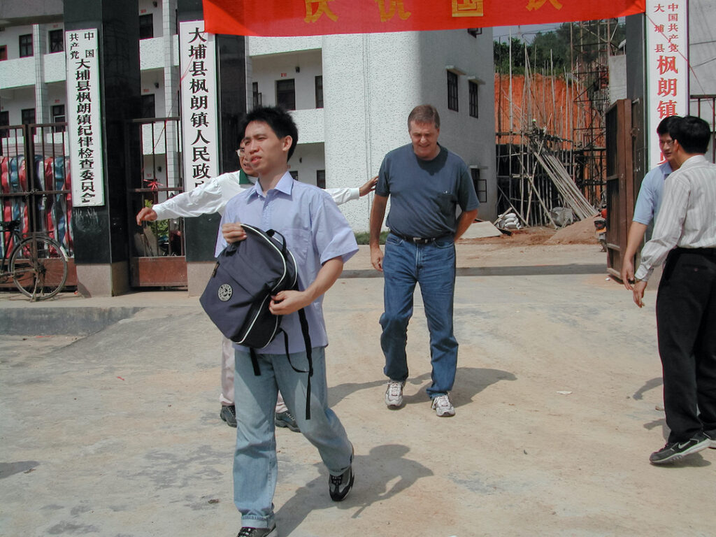 Men walking in a group in a courtyard in Da Pu China 2002