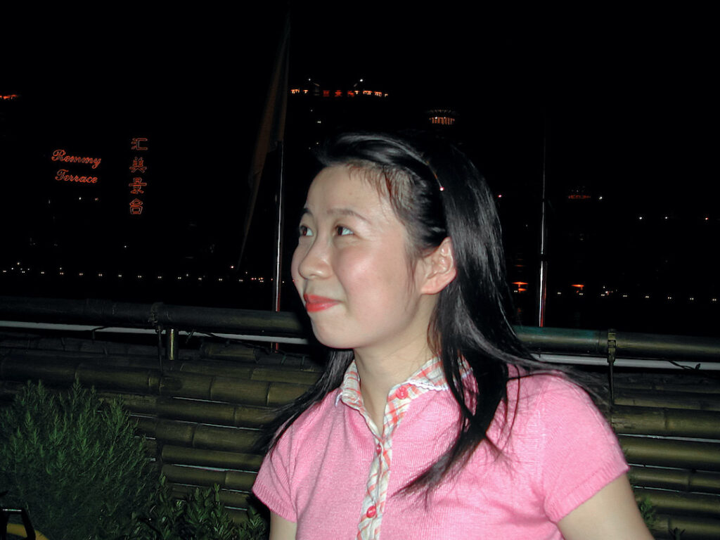 A young woman with dark hair wearing.a pink shirt.