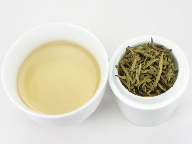 Cupped infusion of Mengding Huangya (Handmade Yellow Buds) yellow tea and strained leaves.