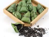Several individual bundles of Qimen Zongzi (Bamboo Keemun) black tea dry leaves in a wooden display box.