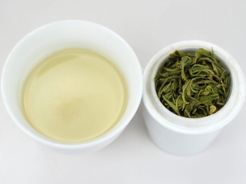 Cupped infusion of Ming Qian Mogan Green tea and strained leaves.