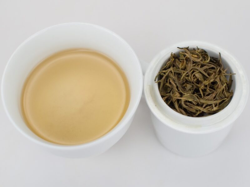 Cupped infusion of Early Spring Mogan Huangya yellow tea and strained leaves.