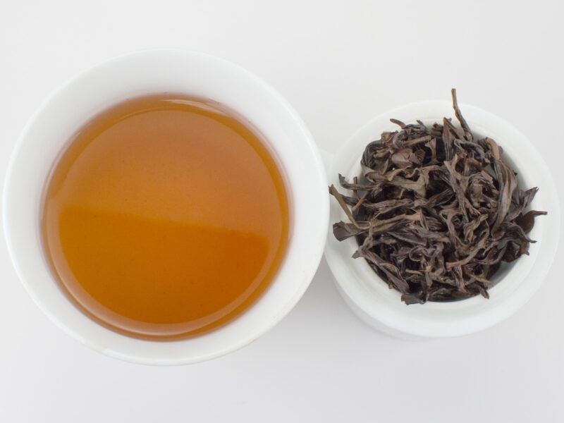 Cupped infusion of Wudong Ba Xian (Wudong Eight Immortals) Dan Cong wulong tea and strained leaves.