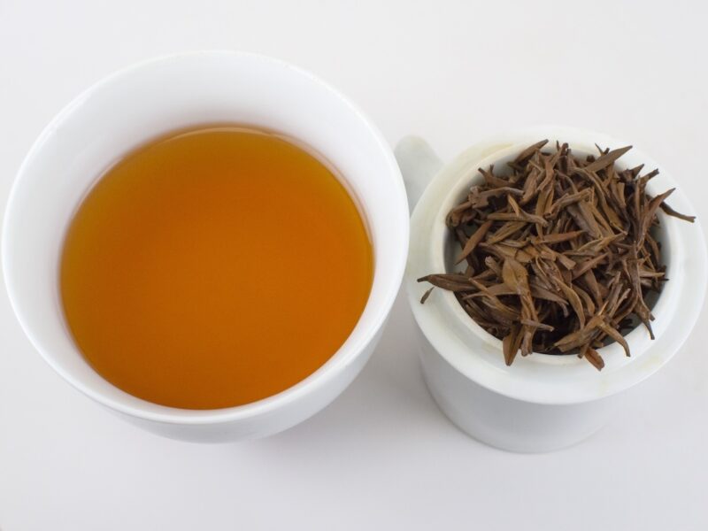 Cupped infusion of Jin Jun Mei (Champion Steed) black tea and strained leaves.