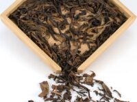 Jingmai Huangpian 2007 puer tea dry leaves in a wooden display box.