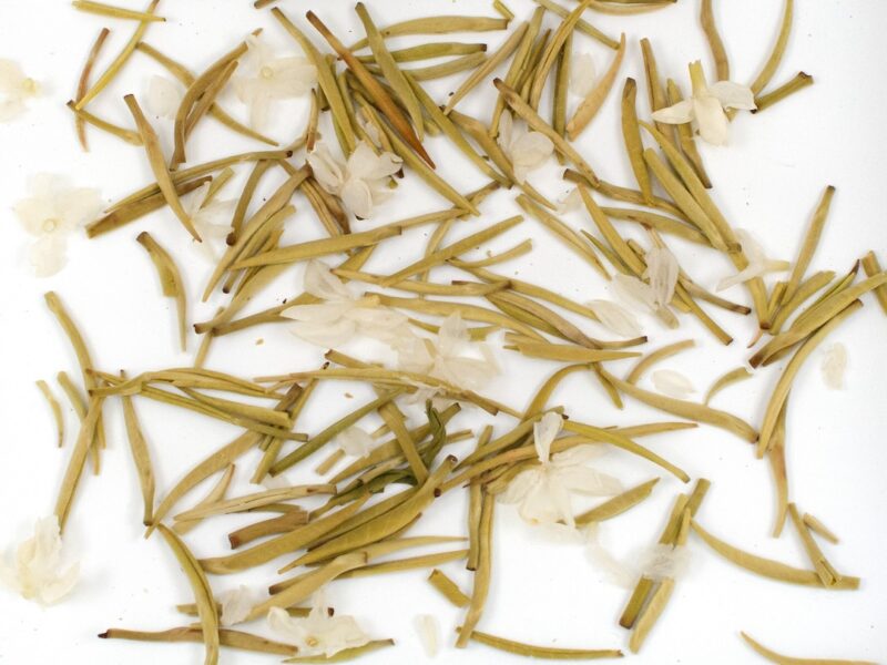 Moli Yinzhen (Jasmine Needle) scented green tea leaves floating in clear water.