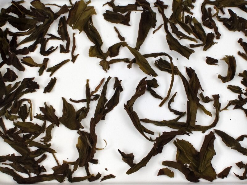 Bai Rui Xiang (Hundred Blooms) rock wulong tea leaves floating in clear water.