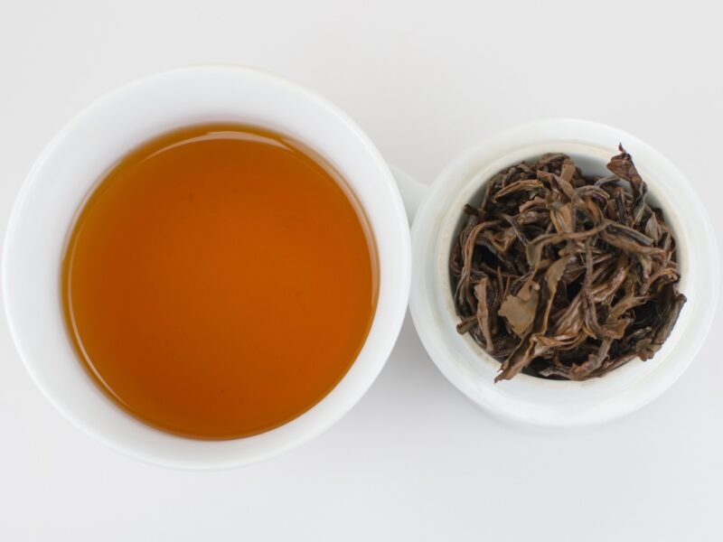 Cupped infusion of Yiwu Sun-Dried Yunnan black tea and strained leaves.