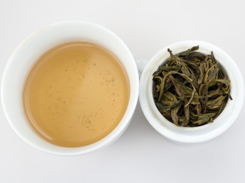 Cupped infusion of Yiwu Guafengzhai sheng puer tea and strained leaves.