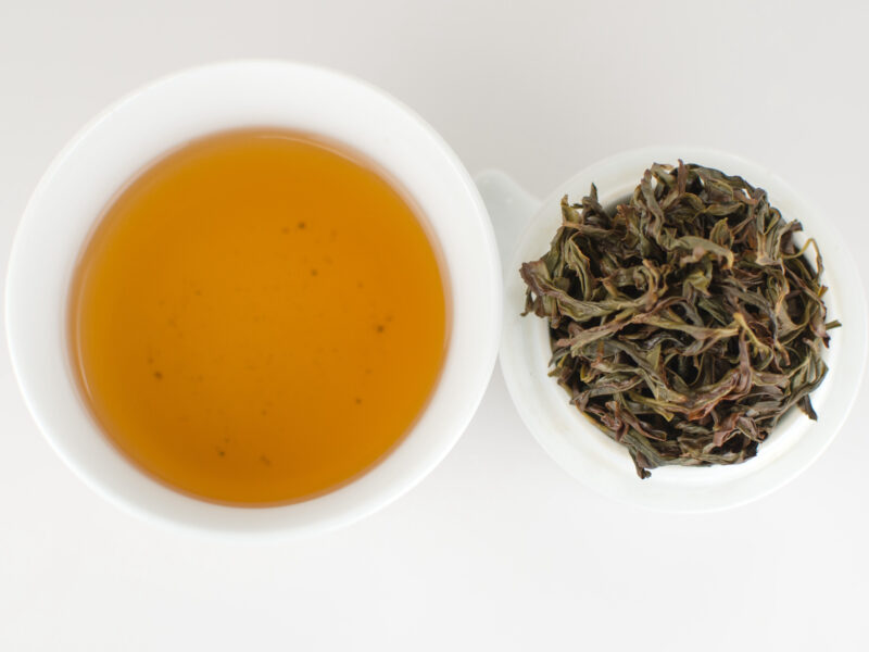 Cupped infusion of Xing Ren Xiang (Almond Blossom) Dan Cong wulong tea and strained leaves.