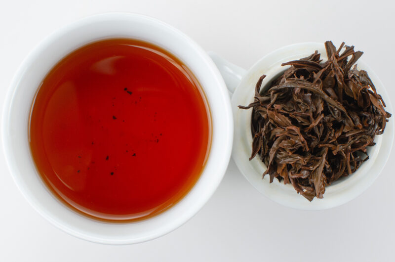Cupped infusion of Feizi Xiao (Concubine's Smile) Wuyi black tea and strained leaves.