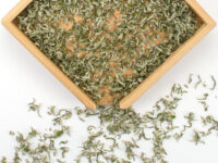 Mengding First Pluck Sweet Dew green tea leaves displayed on a bamboo tray.