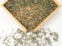 First Pluck Bi Luo Chun green tea dry leaves in a wooden display box.