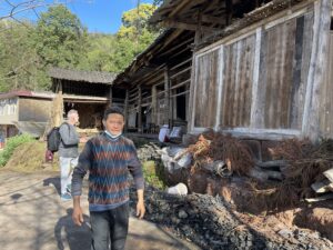 two man standing by a very old wooden house in Mengding Mountain.