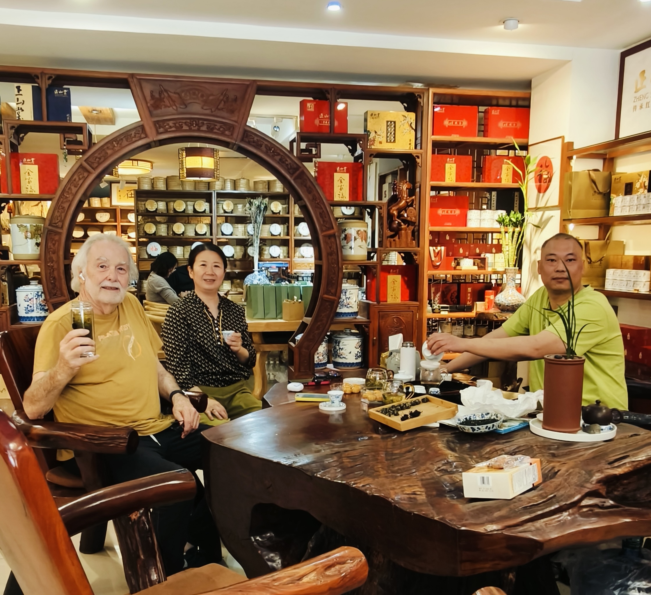 3 people sharing tea, sitting at an ornate tea table surrounded in walls of tea.